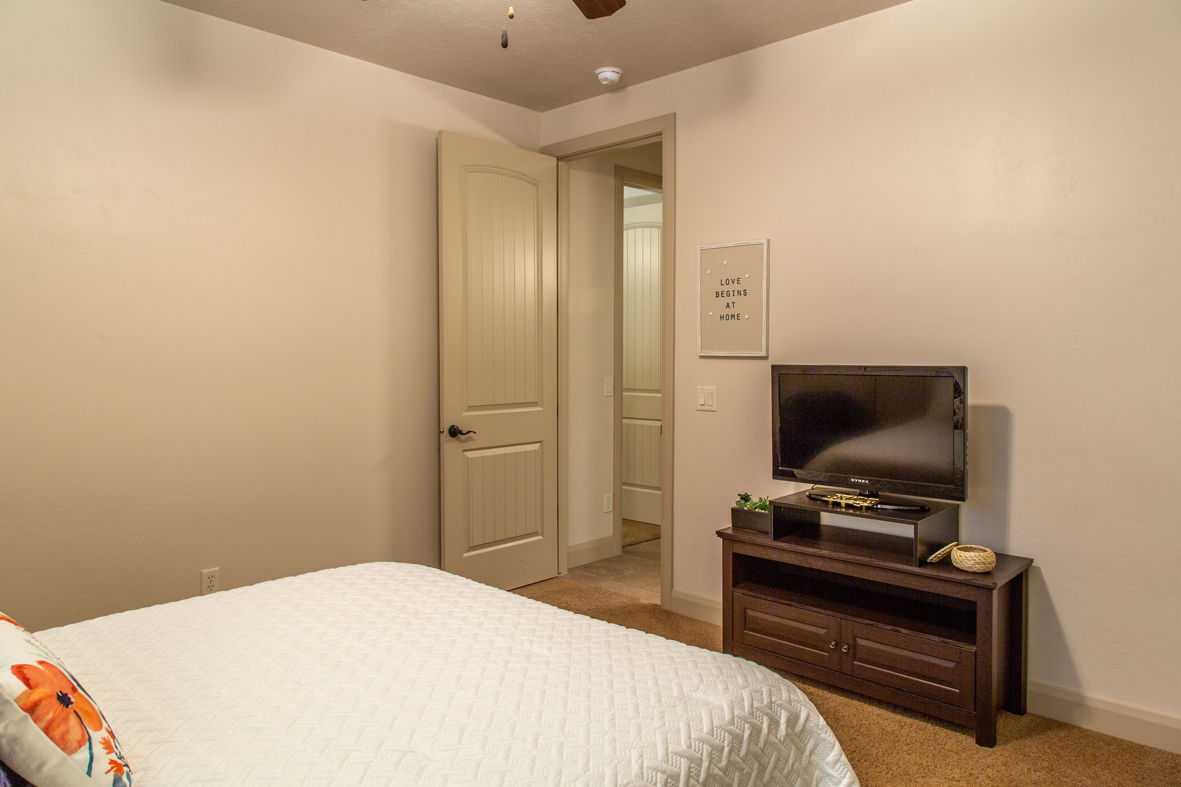 A bedroom with a bed, a television on a stand, a door, and a wall with a sign.