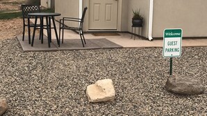 A house with a welcome sign indicating guest parking, a door with a wreath, and outdoor furniture.