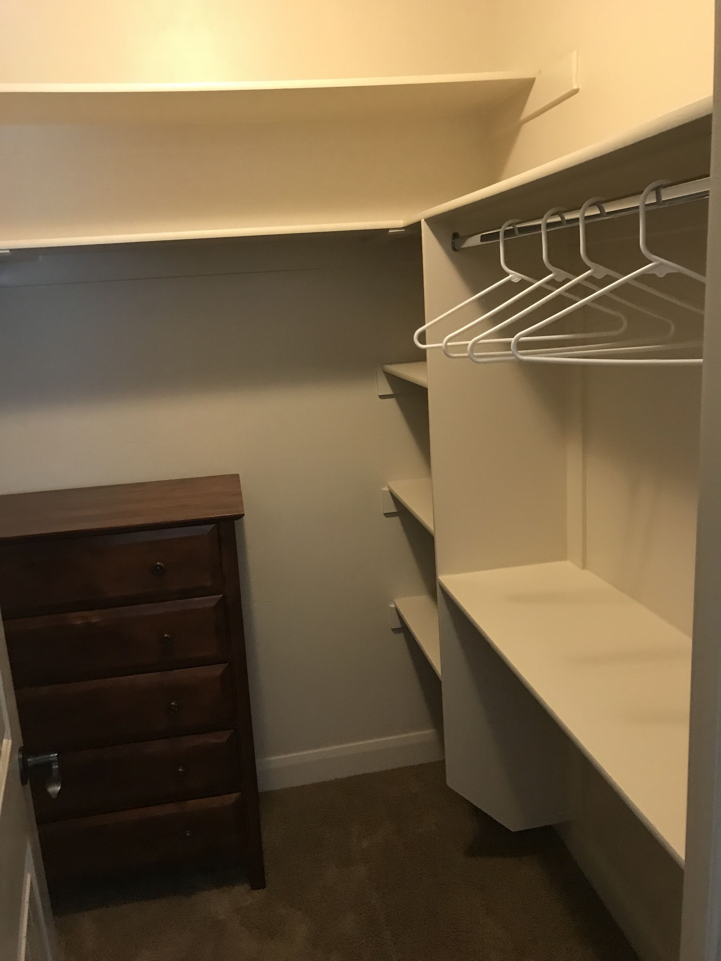 Ein Zimmer mit einem Holzkasten, einer weißen Decke und einem Metallregal.