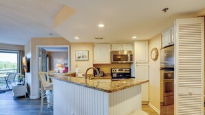 A kitchen with a central island, stainless steel appliances, and a view to the outside.