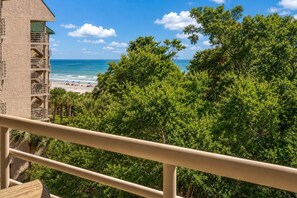Un balcon avec vue sur une plage et l’océan.