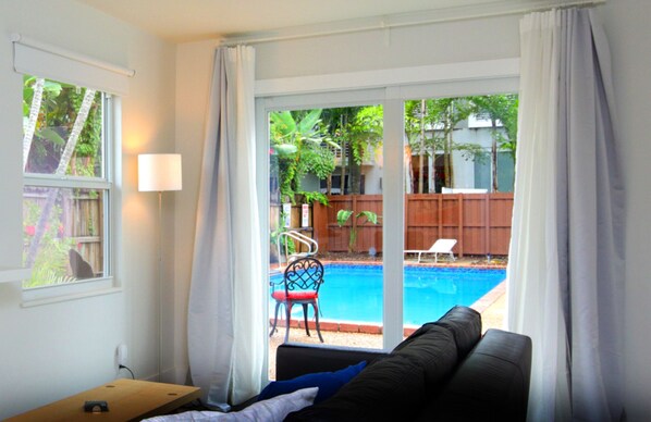 Une chambre avec vue sur une piscine, une chaise et une table.