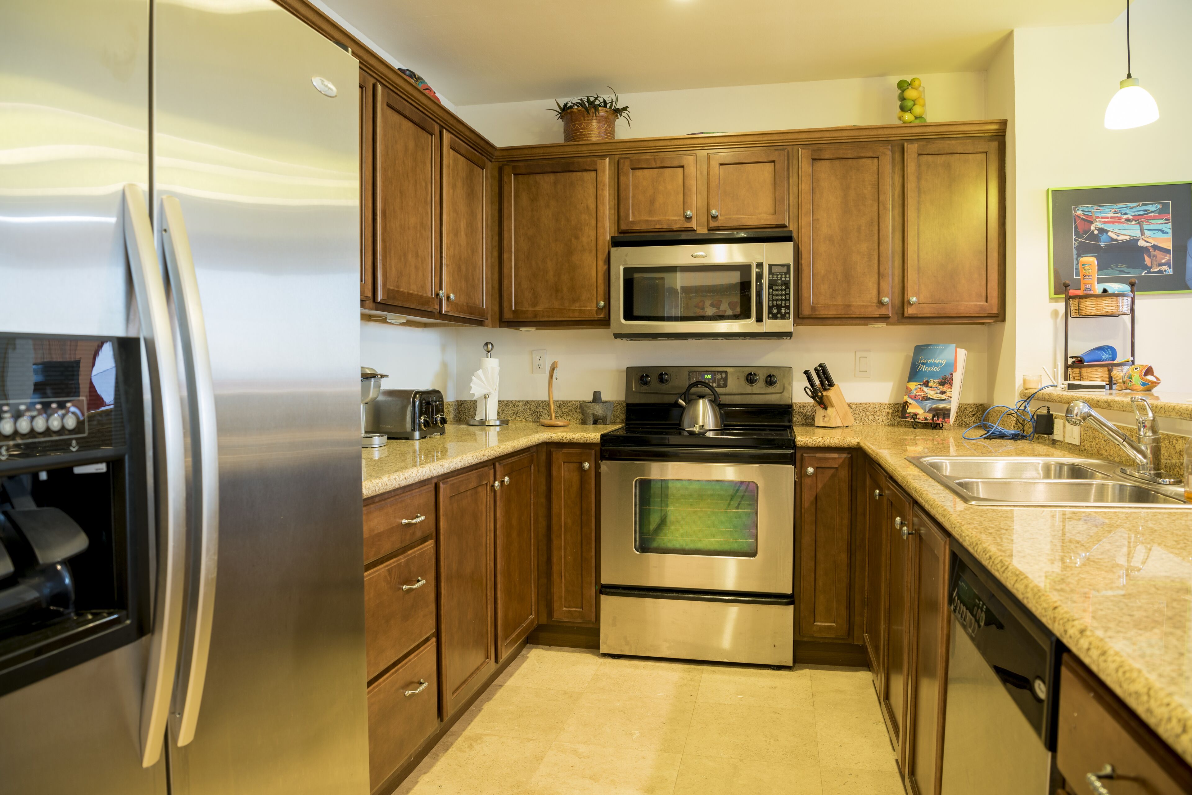 A kitchen with wooden cabinets, stainless steel appliances, a granite countertop, and a sink.