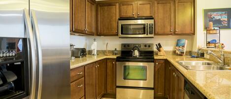 A kitchen with wooden cabinets, stainless steel appliances, a granite countertop, and a sink.