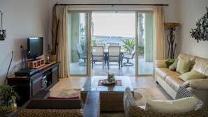 Un salon comprenant un téléviseur, un canapé et un coin repas avec des chaises et une table.