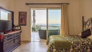 Une chambre avec un lit, une télévision, une commode et une vue sur la plage.
