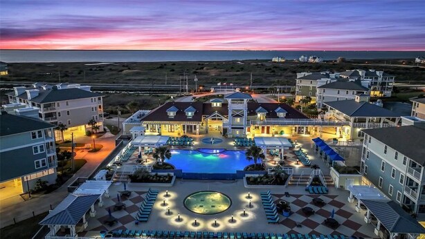 A resort with a central pool, multiple buildings, and a beach view.