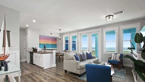 A spacious living area with a large window overlooking the sea, a cozy seating area, and a modern kitchen.