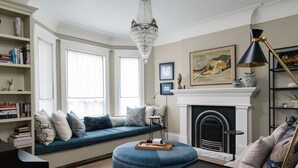 A living room with a blue sofa, a fireplace, a chandelier, and a bookshelf.