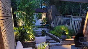 A covered patio area with outdoor seating, potted plants, and a fire pit.