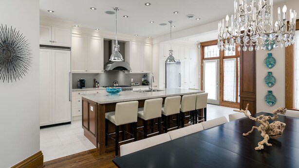 A modern kitchen with white cabinets, a central island, and a chandelier.
