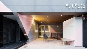 Ein modernes Interieur mit einer Rezeption, einer Sitzecke und einem Glastür-Eingang.