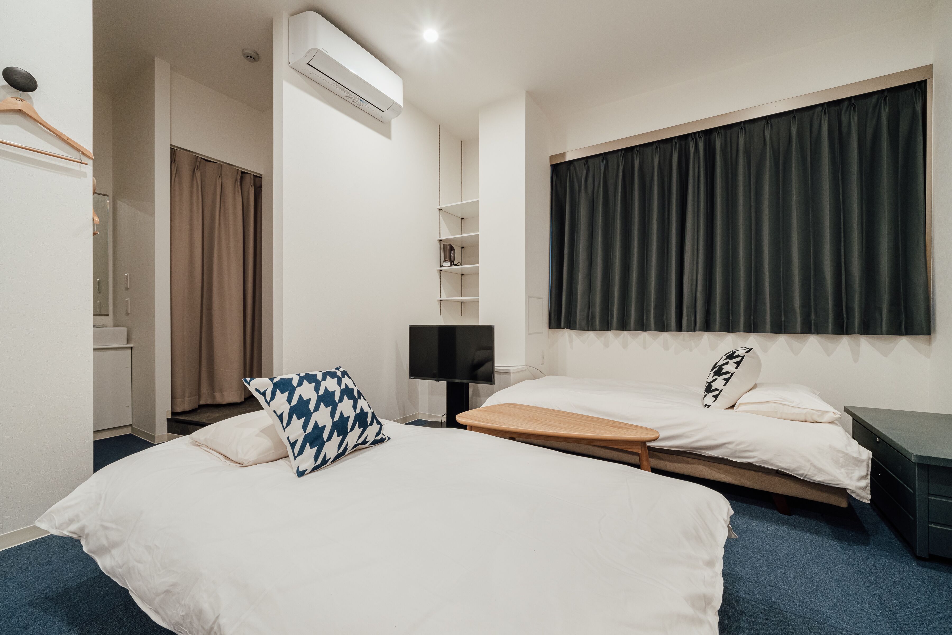 A hotel room with two beds, a TV, a wardrobe, and a bathroom.