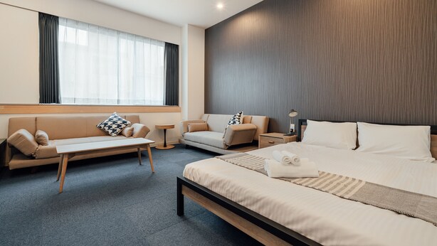 Ein modernes Hotelzimmer mit einem großen Bett, einer Couch, einem kleinen Tisch und einem Nachttisch.