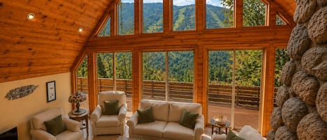 A spacious room with a high ceiling and large windows offering a mountain view.