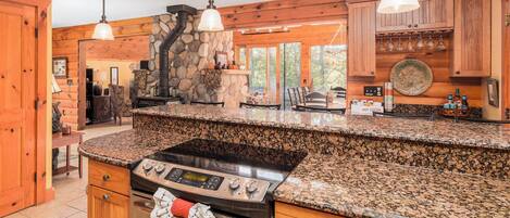A kitchen with granite countertops, a stove, and wooden cabinetry.