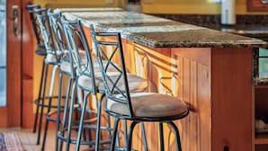 Una cocina con una barra de madera y taburetes de metal.