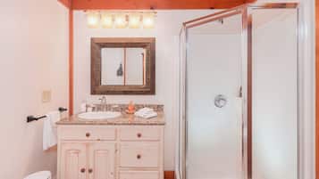 Un baño con techo de madera, un lavabo con espejo y una zona de ducha.