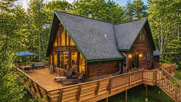 Una cabaña con terraza, mobiliario exterior y una escalera.