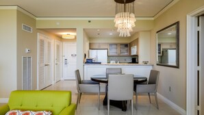 Zona pranzo con tavolo rotondo, sedie, un lampadario e una cucina sullo sfondo.