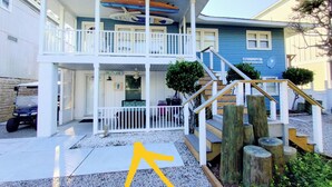 A two-story building with a covered porch, a staircase, and a sign that reads "Hi Tide."