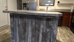 A kitchen with a wooden island countertop and a stainless steel refrigerator.