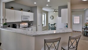 A modern kitchen with white cabinets, a built-in microwave, and a granite countertop. - SUN CITY GEORGETOWN, TX RESORT - STUNNING CONTEMPORARY! (Georgetown)