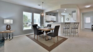 A dining area with a wooden table, four chairs, a lamp, and a rug. - SUN CITY GEORGETOWN, TX RESORT - STUNNING CONTEMPORARY! (Georgetown)