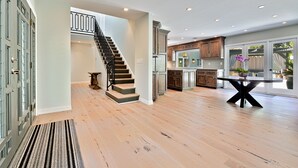 Eine geräumige Küche mit modernen Geräten, ein Essbereich mit einem runden Tisch und eine Treppe, die in einen oberen Bereich führt.