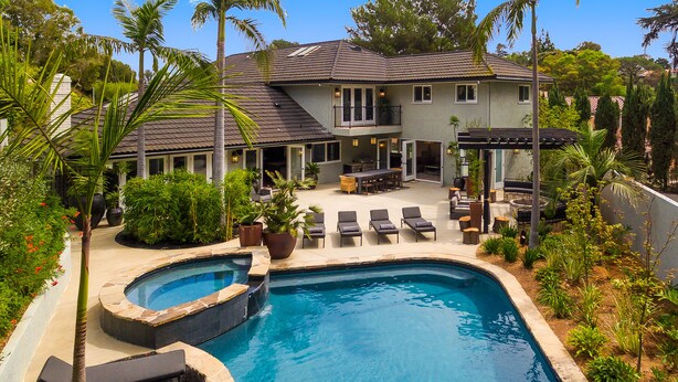 Ein Pool mit integriertem Whirlpool, umgeben von Liegestühlen und einer überdachten Terrasse.
