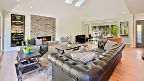 Ein geräumiges Wohnzimmer mit einer Ledersofa, einem Kamin und einem Essbereich inklusive Tisch und Stühlen.