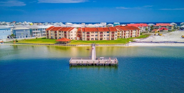 A waterfront hotel with multiple buildings, a dock, and a clear view of the ocean.