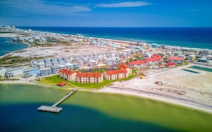 An aerial view of a coastal resort with multiple buildings, a pier, and a beach.