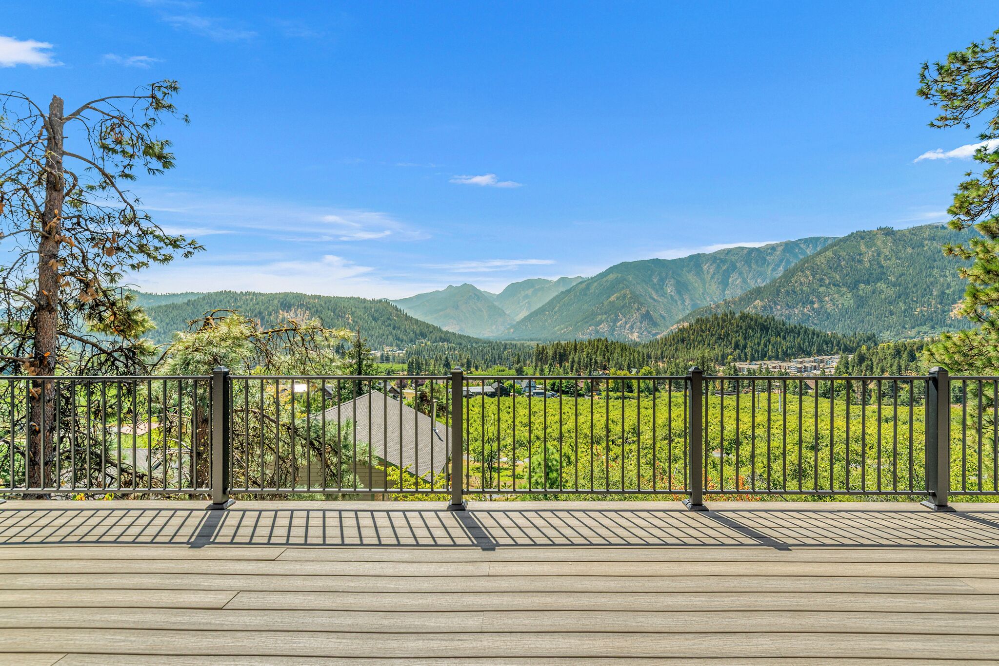Una terrazza in legno con ringhiera in metallo affacciata su un paesaggio montuoso.