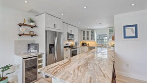 Una cocina moderna con armarios blancos, electrodomésticos de acero inoxidable y encimera de mármol.