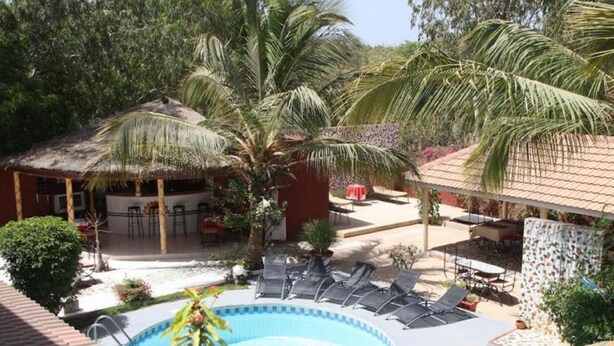 A pool area with lounge chairs, a bar, and palm trees. - Grazia Maria Hotel (Mbour)