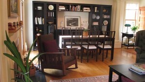 A living room with a dining area, featuring a fireplace, bookshelves, and a large painting.