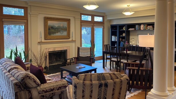 A living room with a fireplace, a dining area, and a bookshelf.