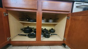 Un mueble de madera con dos estantes, cada uno con distintos utensilios y utensilios de cocina.