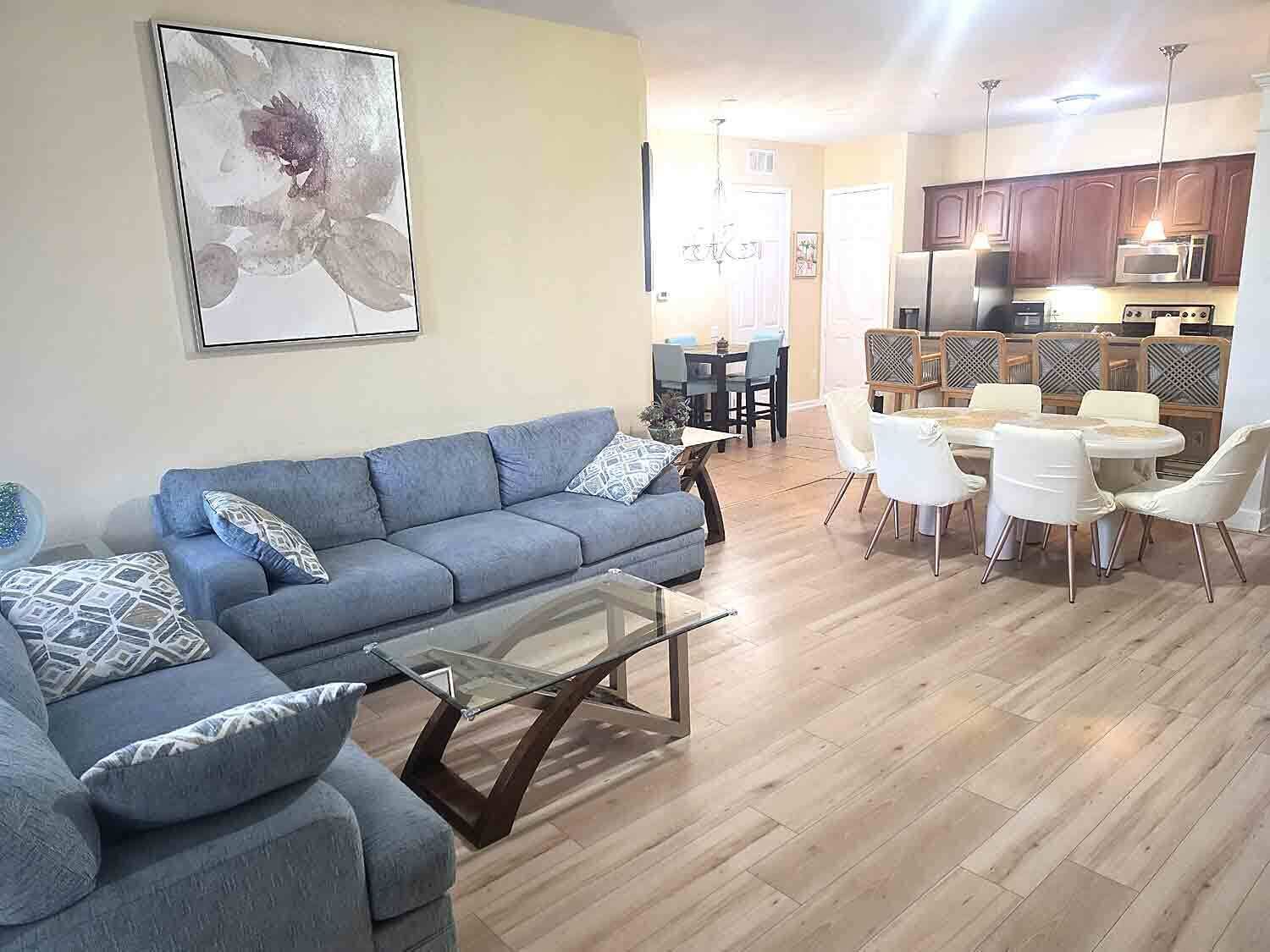 A living room with a sofa, a glass coffee table, and a dining area with chairs and a table.