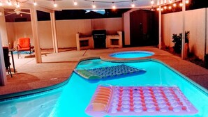 En trädgård med en pool, uppblåsbara solstolar och ljusslingor.