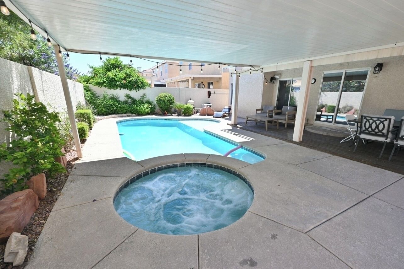 A backyard with a swimming pool, hot tub, and outdoor seating area.