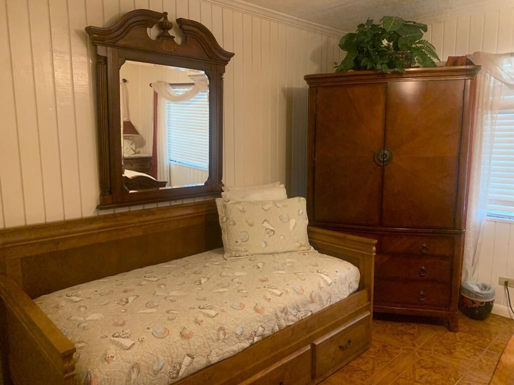A bedroom with a wooden bed, a large wardrobe, and a mirror.