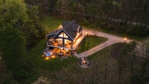 Una casa grande con porche, una chimenea exterior y un espacio al aire libre bien iluminado.
