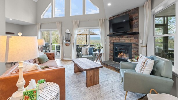Un salón espacioso con chimenea, ventanas amplias y un balcón.