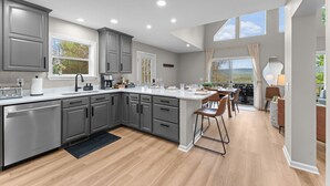 Una cocina moderna con armarios grises, una isla central y un comedor con vistas.