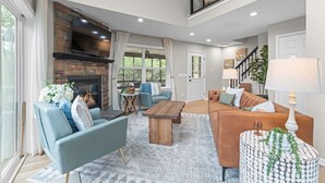 Una sala de estar amplia con chimenea, un comedor y un balcón.