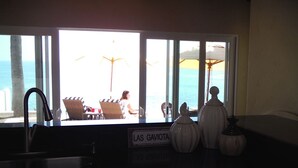 Une cuisine avec vue sur la plage, une enseigne indiquant « LAS GAVIOTA », et des vases décoratifs.
