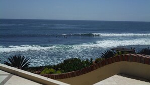 Une vue sur la côte, avec des vagues, un espace patio et une rambarde.