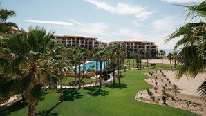 A resort with multiple buildings, a swimming pool, and a well-maintained lawn with palm trees. - Beguiling pool-ocean view unit (La Paz)